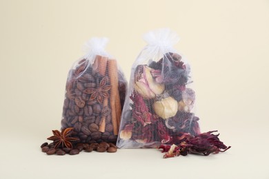 Scented sachets with dried roses, coffee beans, anise and cinnamon on beige background