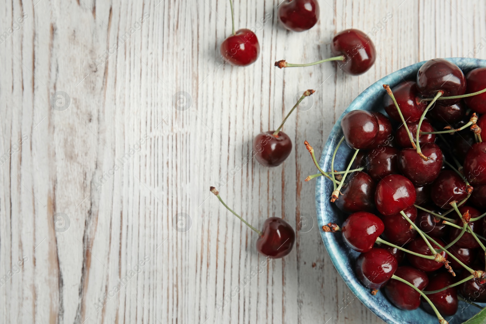 Photo of Bowl with sweet red cherries on wooden table, top view