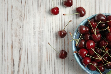 Photo of Bowl with sweet red cherries on wooden table, top view