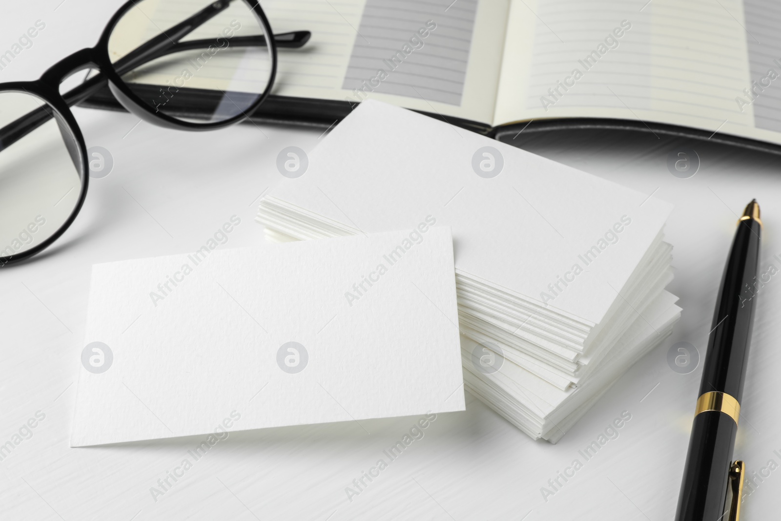 Photo of Blank business cards, glasses and pen on white table. Mockup for design