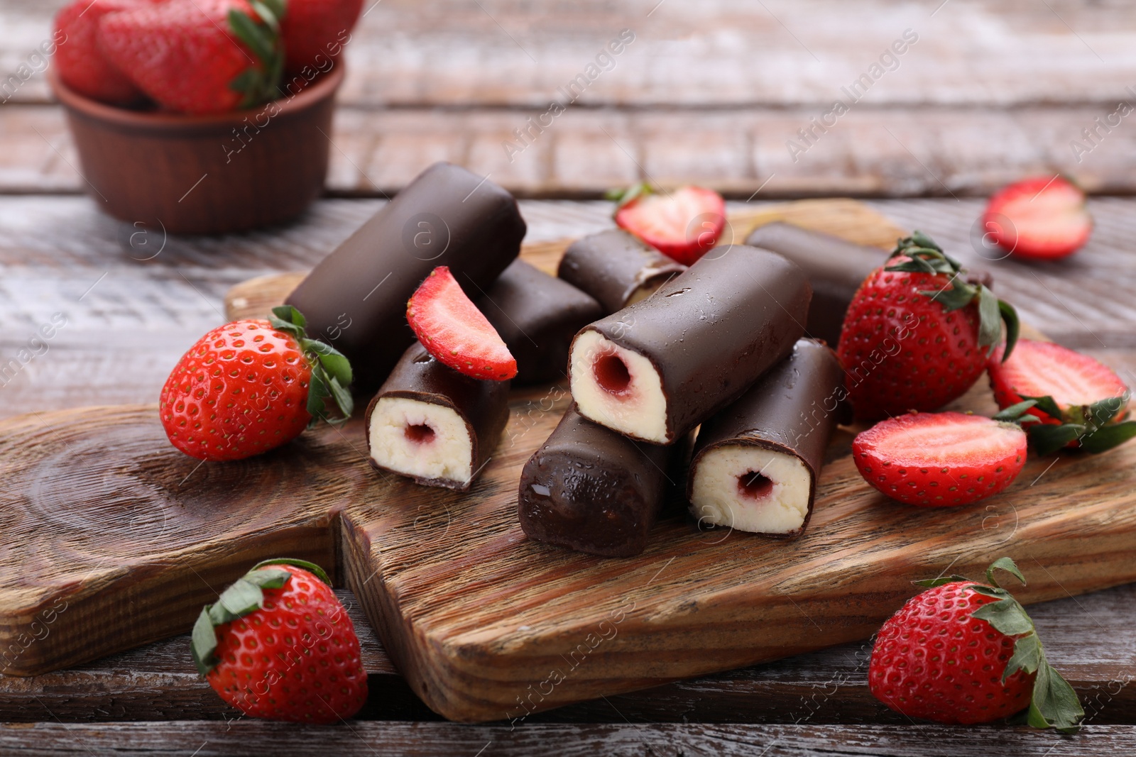 Photo of Delicious glazed curd snacks with fresh strawberries on wooden table