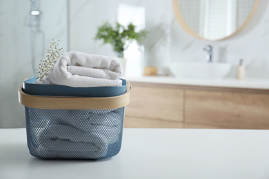 Photo of Basket with clean soft towels in bathroom. Space for text