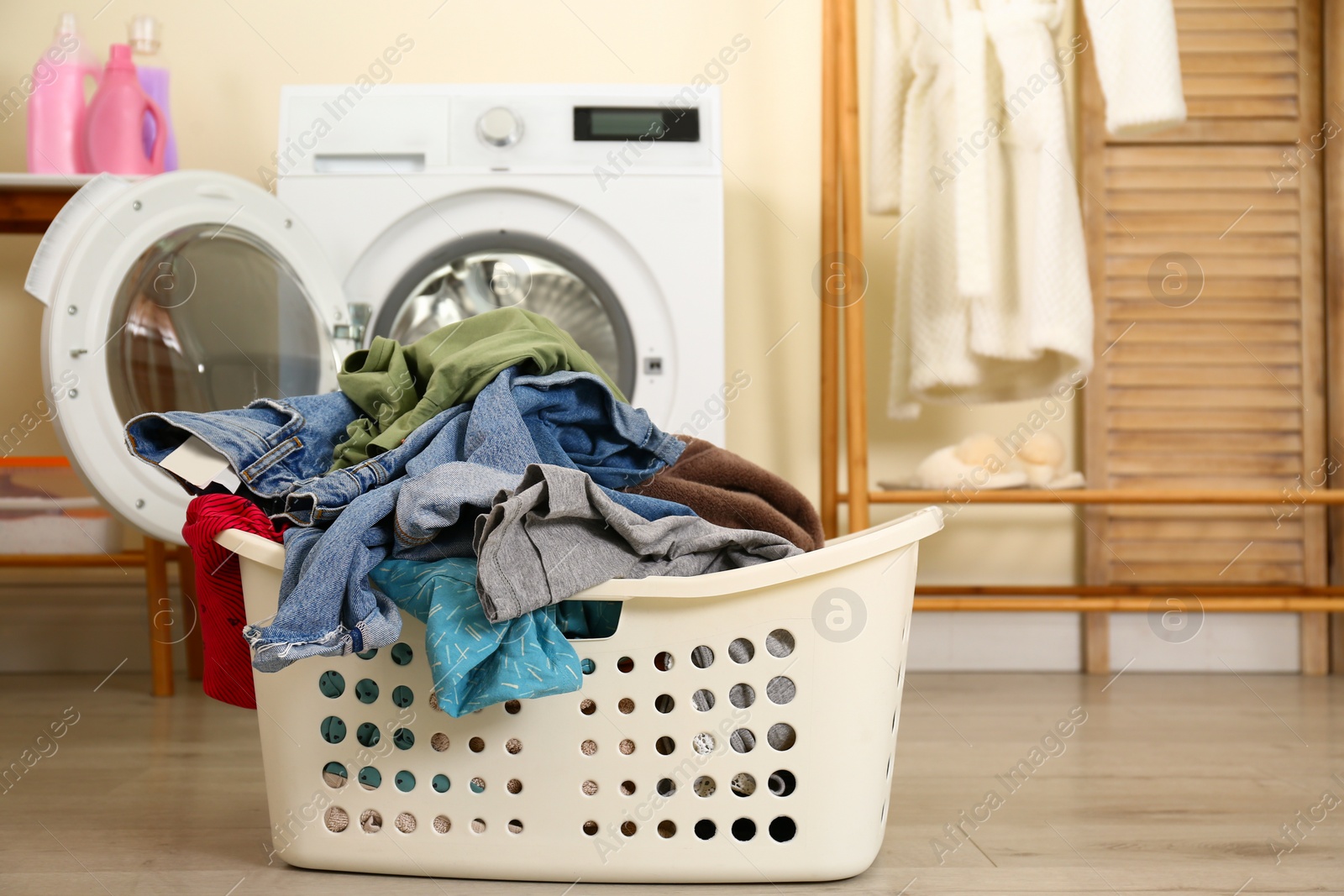 Photo of Basket with dirty laundry near washing machine indoors