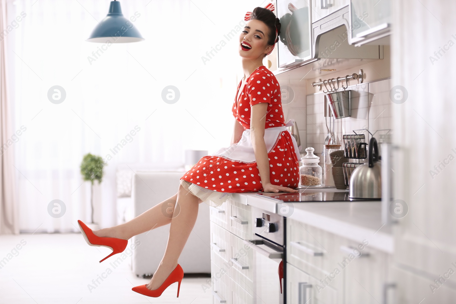 Photo of Funny young housewife sitting on kitchen counter