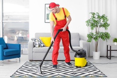 Mature man hoovering carpet with vacuum cleaner in living room