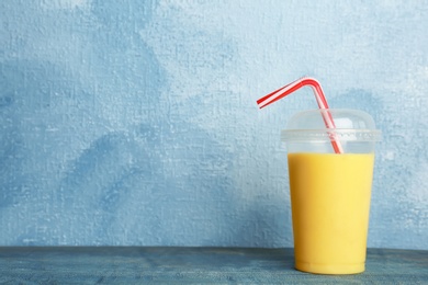 Plastic cup with delicious detox smoothie on table