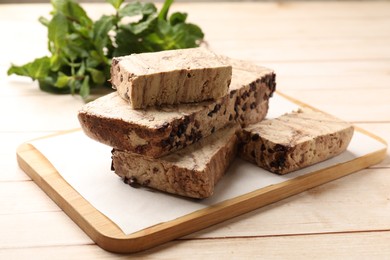 Photo of Pieces of tasty chocolate halva on wooden table, closeup