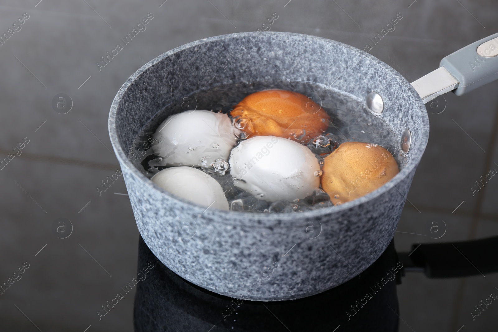 Photo of Chicken eggs boiling in saucepan on electric stove, closeup