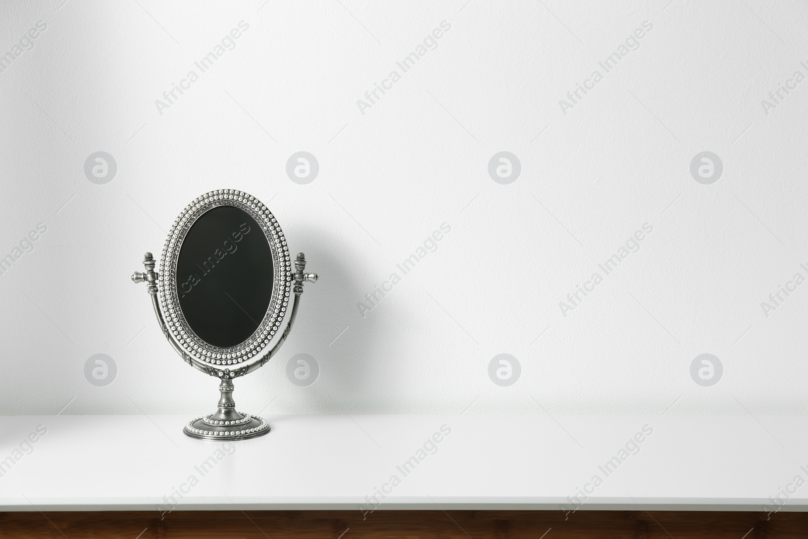 Photo of Small mirror on table near white wall. Space for text