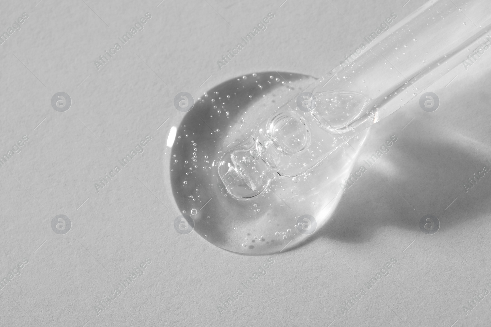 Photo of Pipette with cosmetic serum on light background, macro view