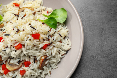 Photo of Delicious rice pilaf with mushrooms on grey table, closeup
