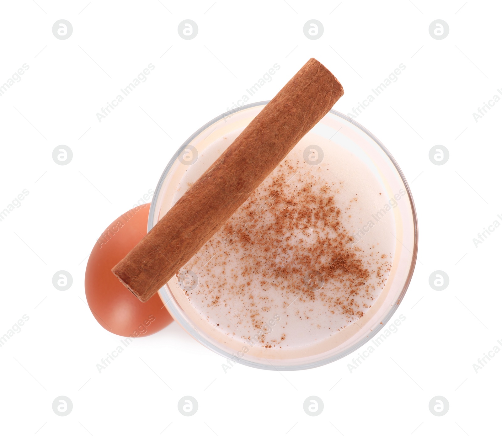 Photo of Delicious eggnog in glass, cinnamon and egg isolated on white, top view