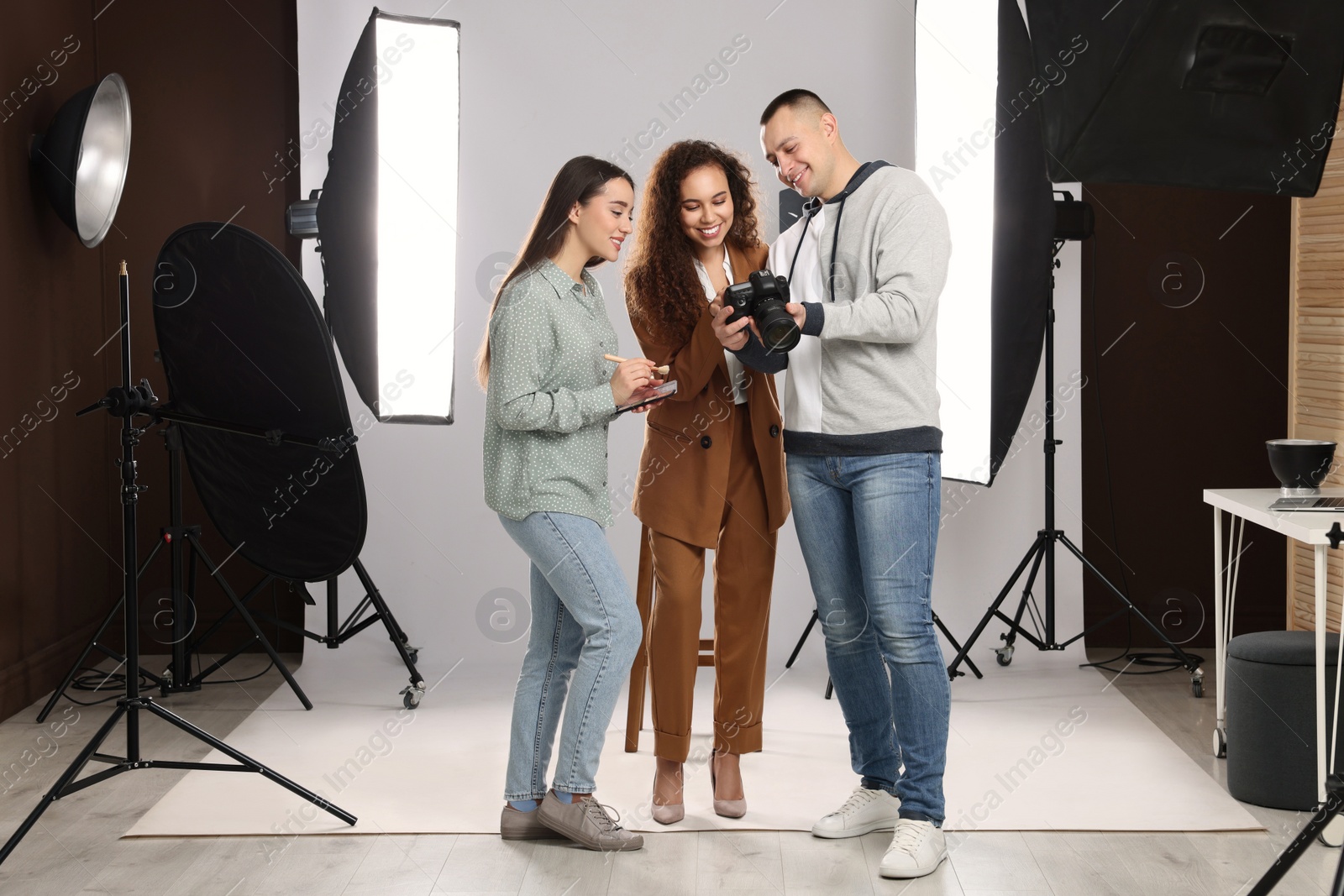 Photo of Professional photographer and makeup artist with model in studio