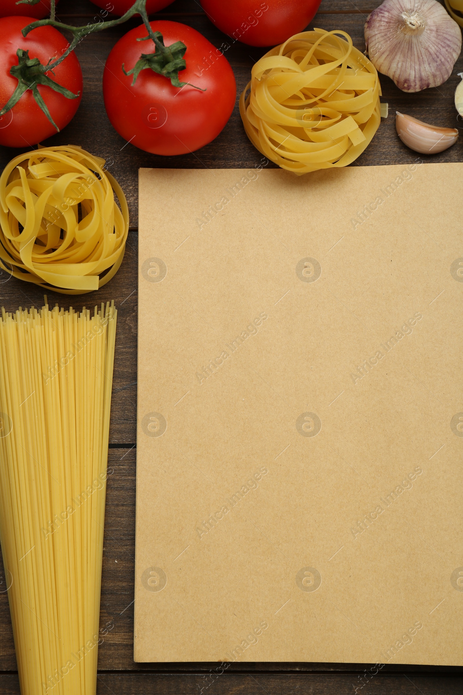 Photo of Blank recipe book and different ingredients on wooden table, flat lay. Space for text