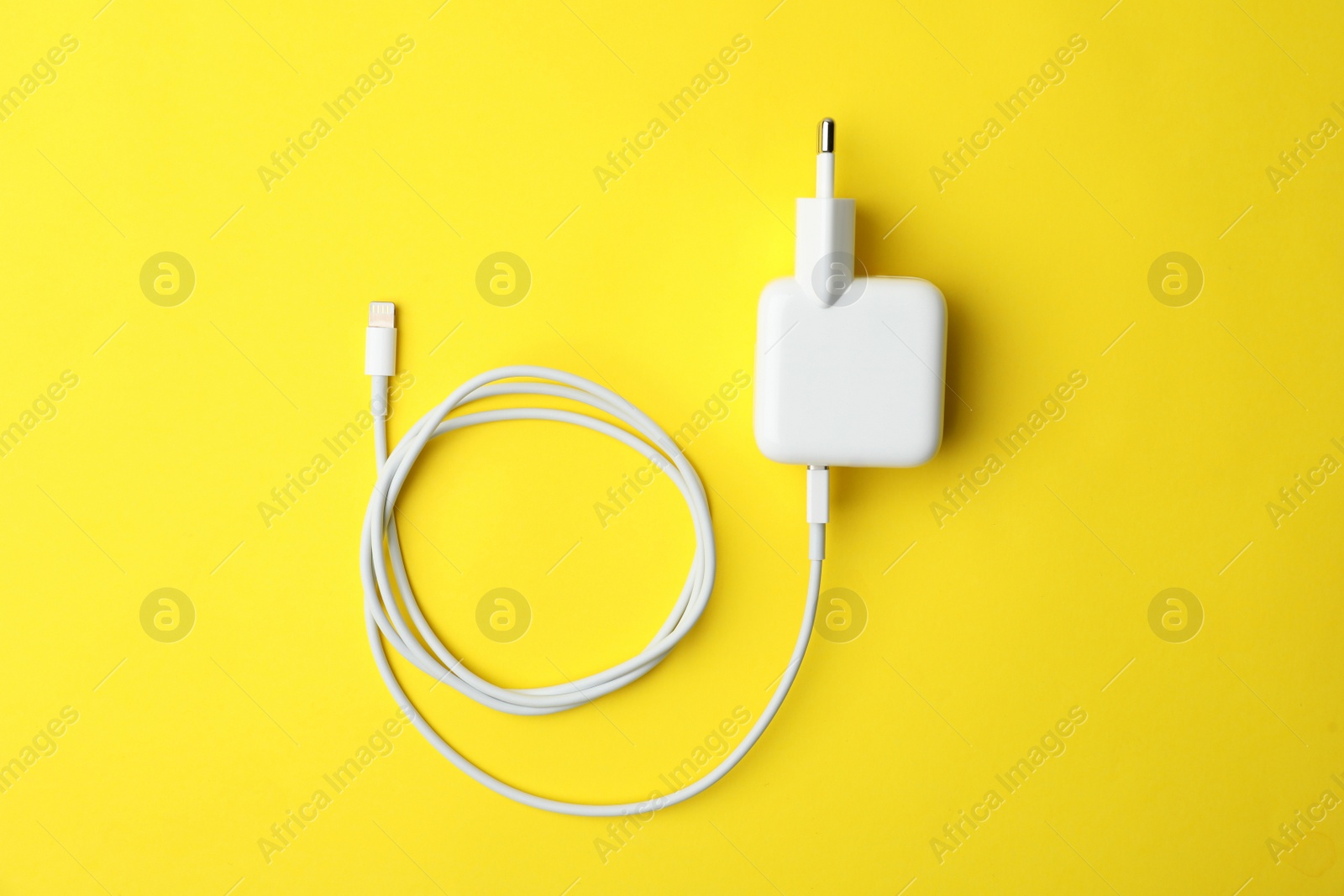 Photo of USB charger on yellow background, top view. Modern technology