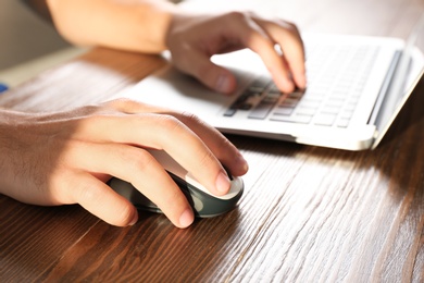 Man using computer mouse with laptop at table, closeup