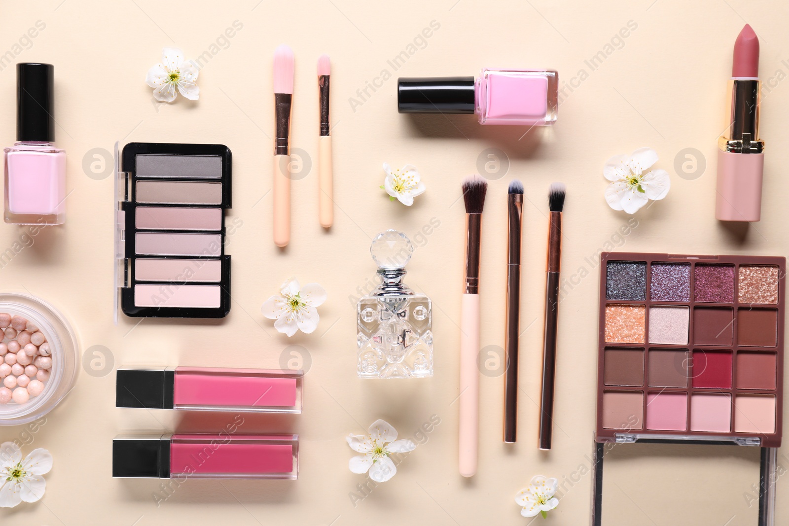 Photo of Flat lay composition with different makeup products and beautiful spring flowers on beige background