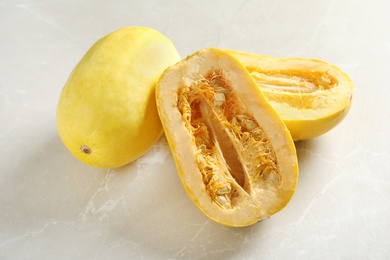 Photo of Whole and cut spaghetti squash on gray table