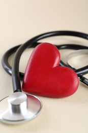 Photo of Stethoscope and red heart on beige background