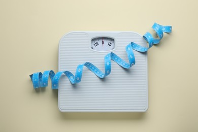 Photo of Scales and measuring tape on beige background, top view