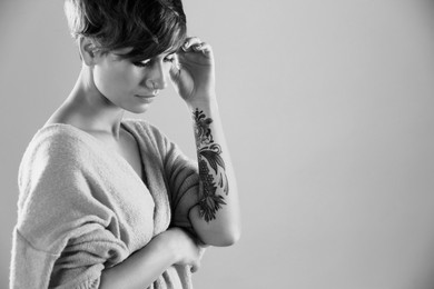 Image of Young woman with tattoo on light background, space for text. Black and white photography