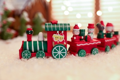 Photo of Decorative train toy on artificial snow, closeup. Christmas atmosphere