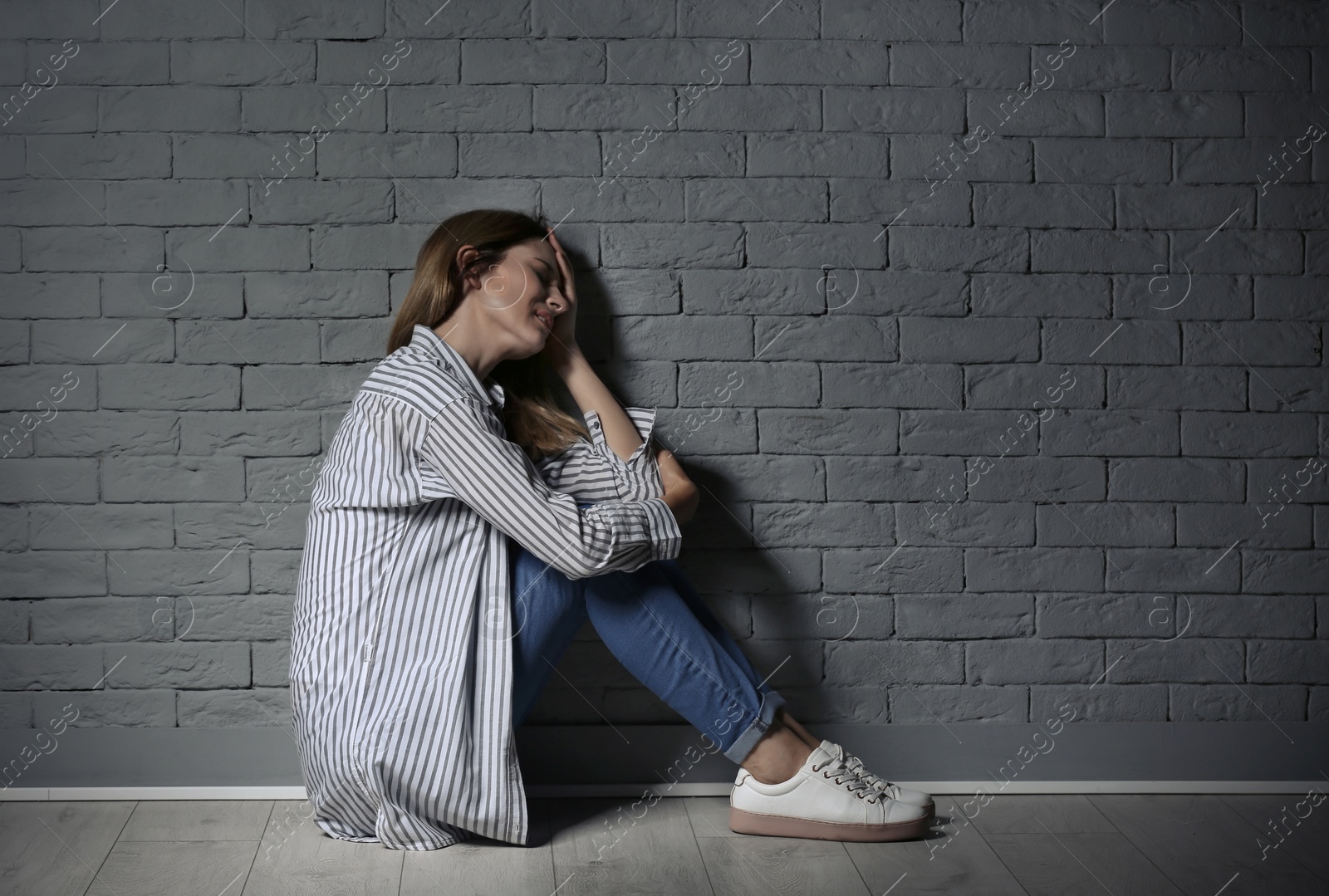 Photo of Lonely woman suffering from depression near brick wall