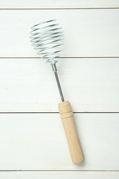 Photo of Metal spring whisk on white wooden table, top view