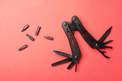 Photo of Compact portable black multitool and details on red background, flat lay