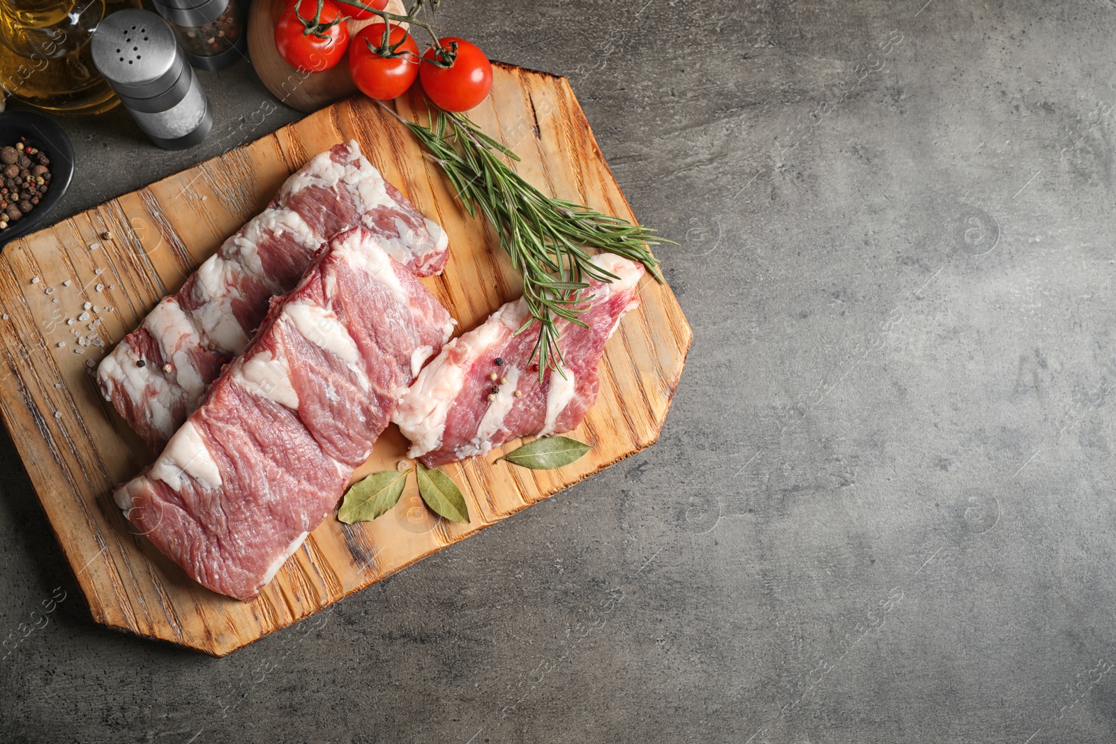 Photo of Raw ribs with herbs and spices on grey table, flat lay. Space for text