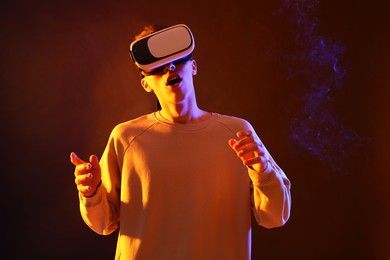 Photo of Young man with virtual reality headset on brown background