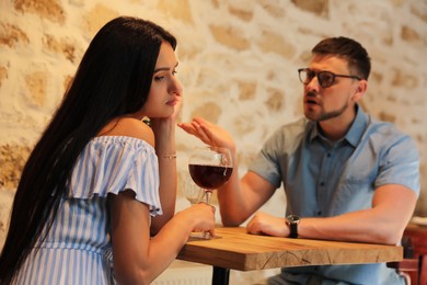 Photo of Young woman getting bored during date with man at cafe