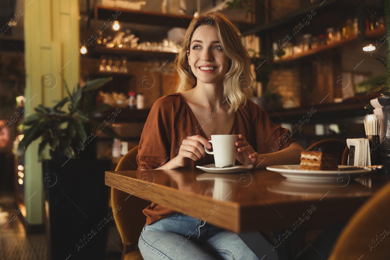 Photo of Young woman with cup of coffee at cafe in morning