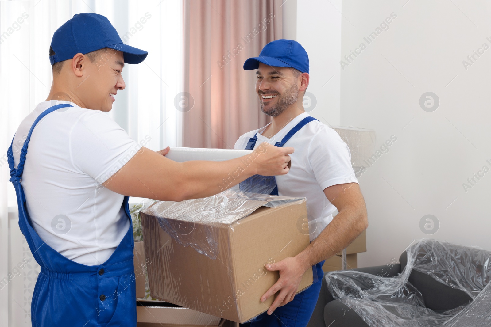 Photo of Workers wrapping box in stretch film indoors