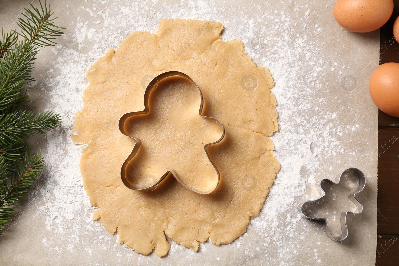 Photo of Making Christmas cookies. Raw dough and cutters on wooden table, flat lay