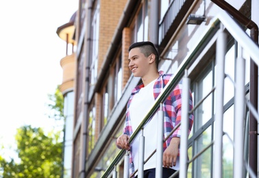 Photo of Young man in stylish outfit outdoors. T-shirt as mockup for design