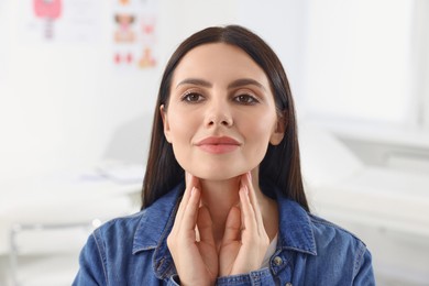 Photo of Endocrine system. Young woman doing thyroid self examination indoors