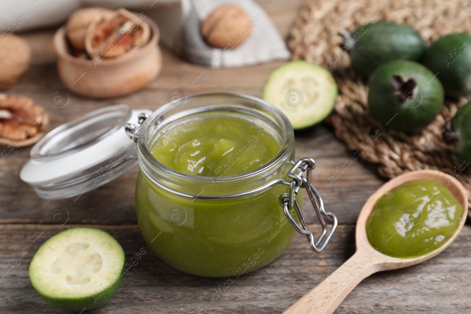 Photo of Glass jar of tasty feijoa jam on wooden table, closeup