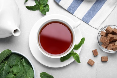 Photo of Flat lay composition with cup of hot aromatic mint tea on light table