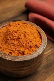 Aromatic saffron powder in bowl on wooden table, closeup