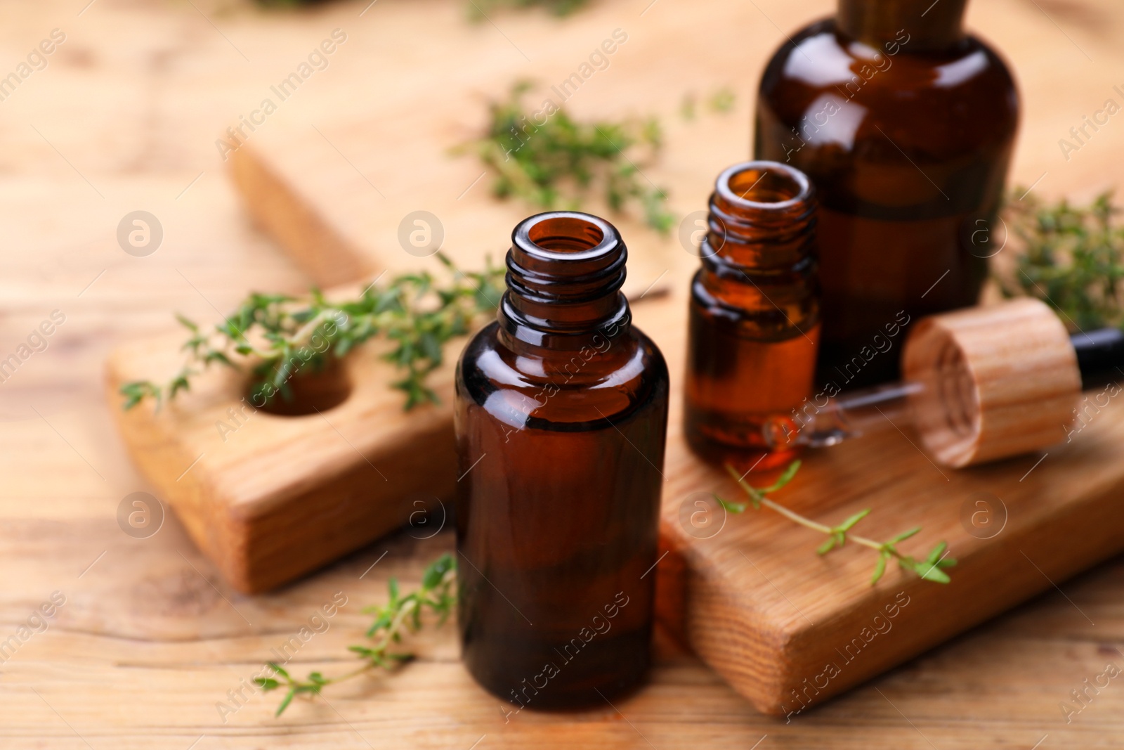 Photo of Thyme essential oil and fresh plant on wooden table