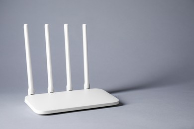 Photo of New stylish Wi-Fi router on grey background. Space for text
