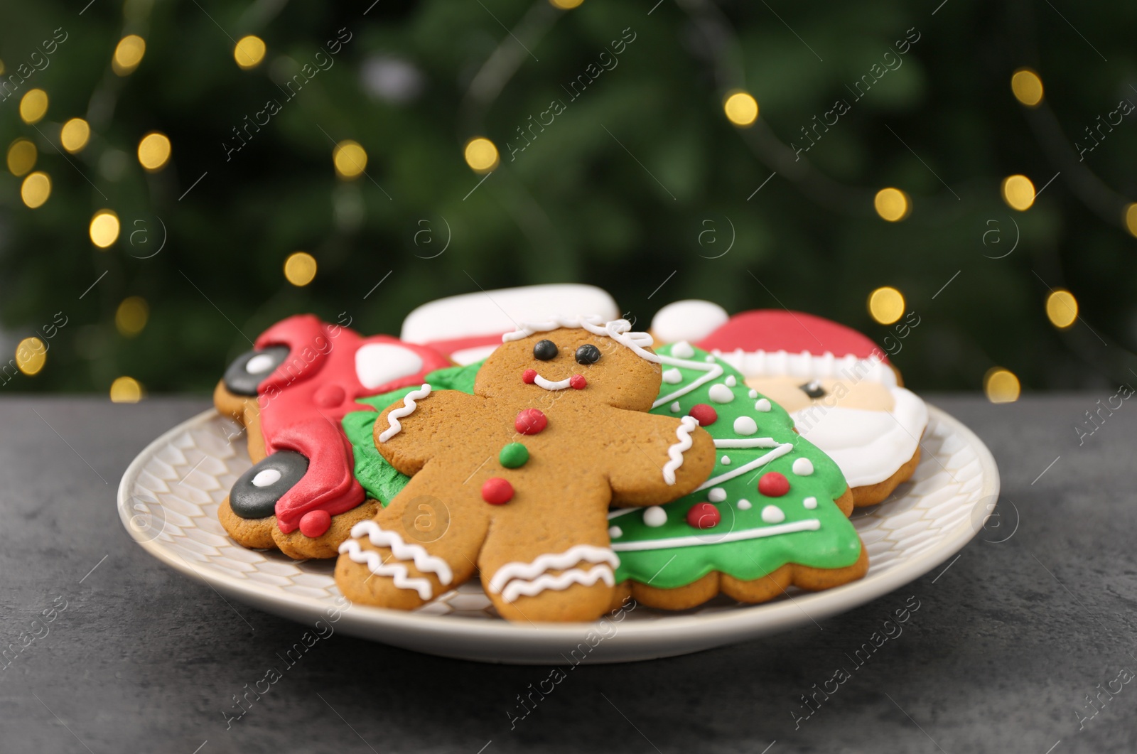 Photo of Decorated cookies on grey table against blurred Christmas lights