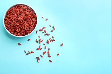 Bowl of dried goji berries on light blue background, top view with space for text. Healthy superfood