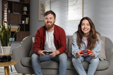 Photo of Couple playing video game with controllers at home