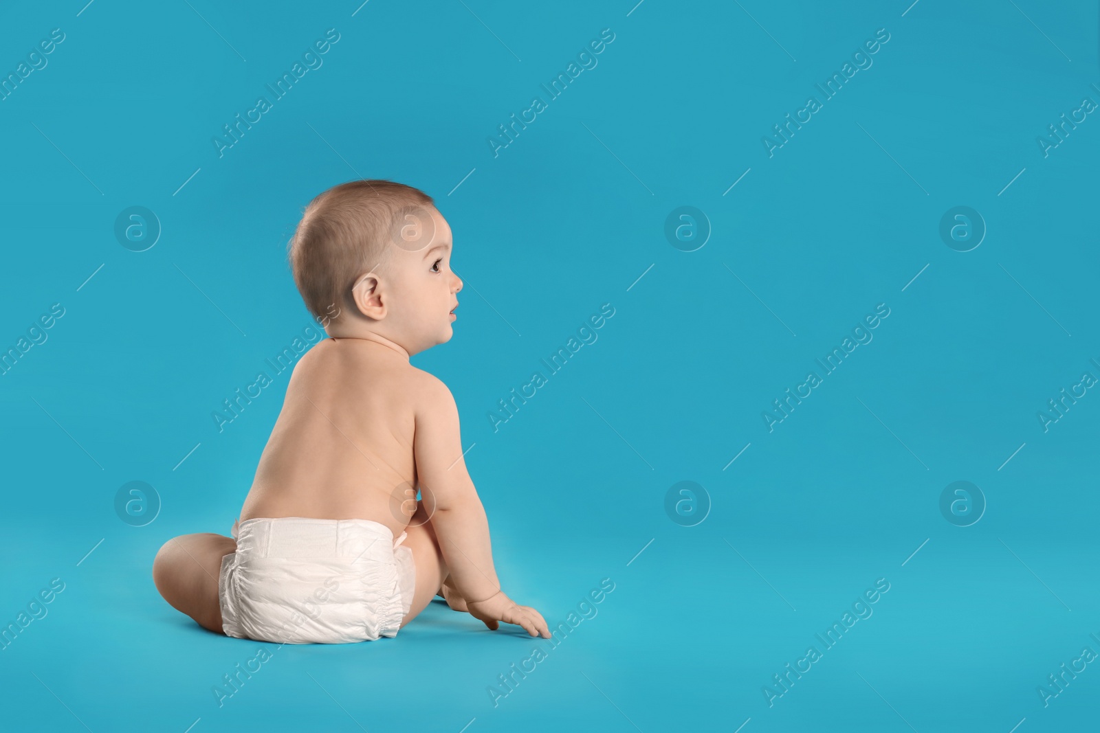 Photo of Cute little baby in diaper on light blue background. Space for text