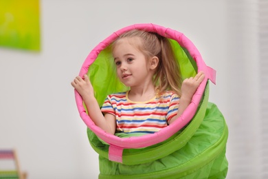 Photo of Cute little child playing with tunnel at home