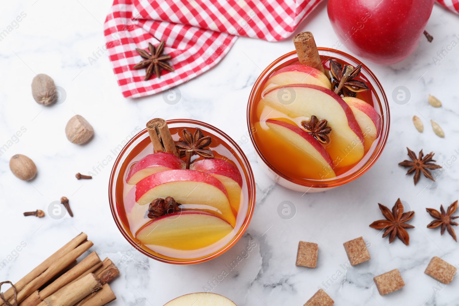 Photo of Aromatic hot mulled cider on white marble table, flat lay