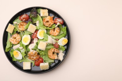 Delicious Caesar salad with shrimps on beige table, top view. Space for text