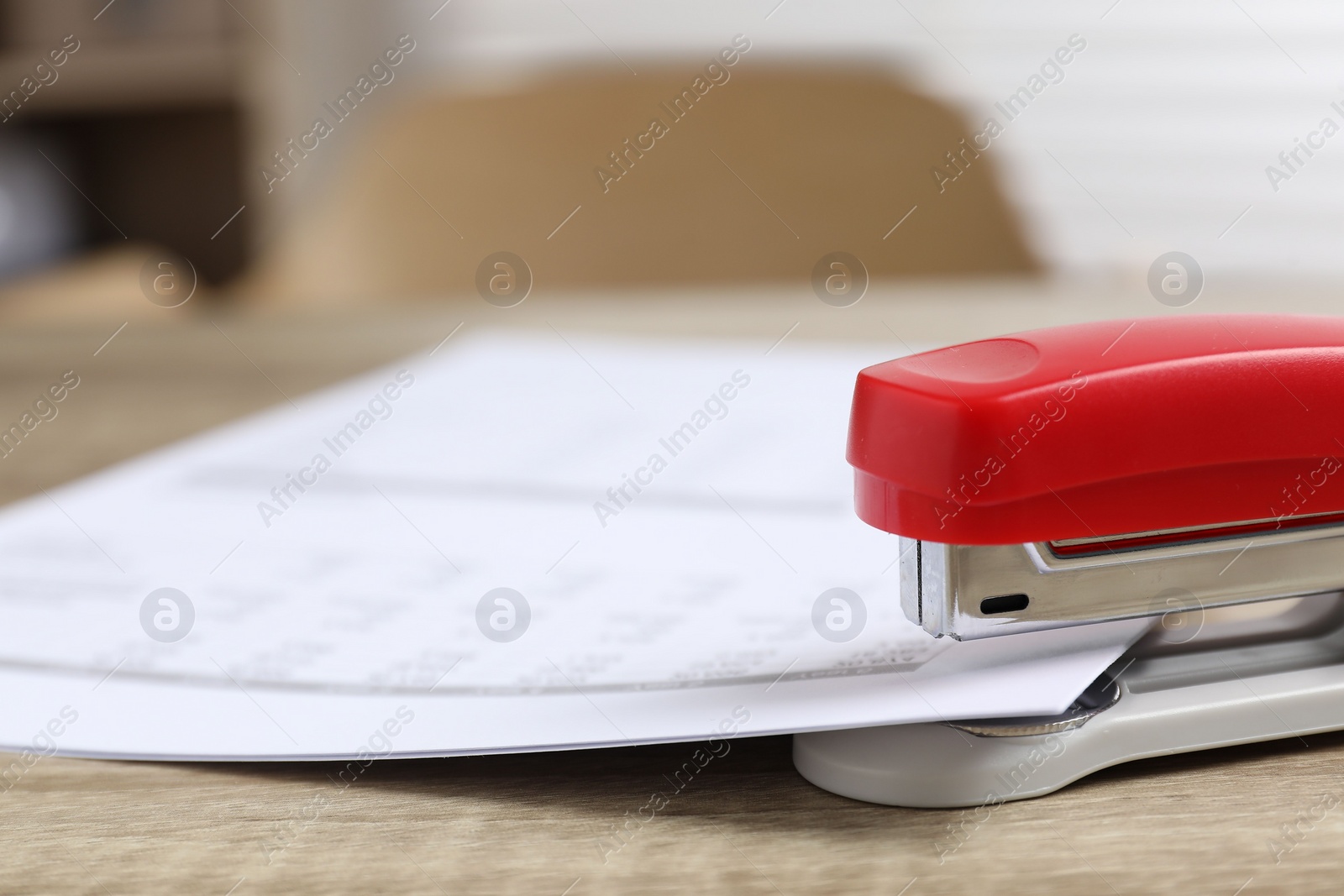 Photo of Bright stapler with documents on wooden table indoors, closeup